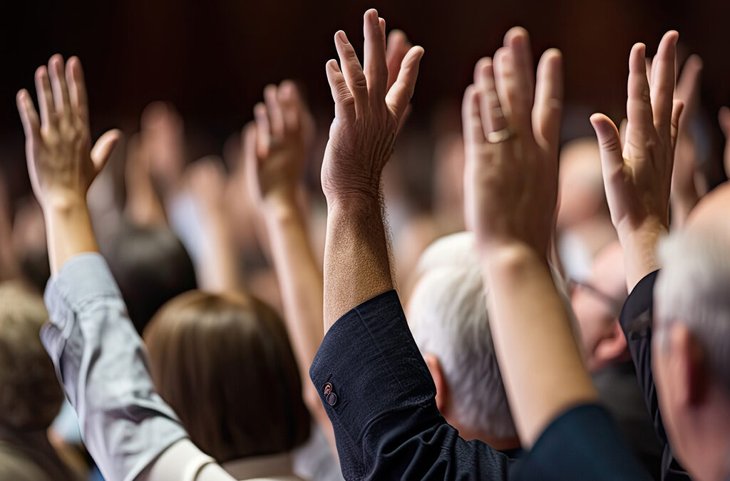 Verschiedene Menschen heben ihre Hand in einer Abstimmung