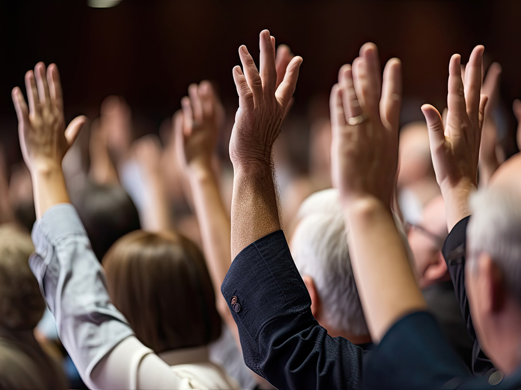 Verschiedene Menschen heben ihre Hand in einer Abstimmung
